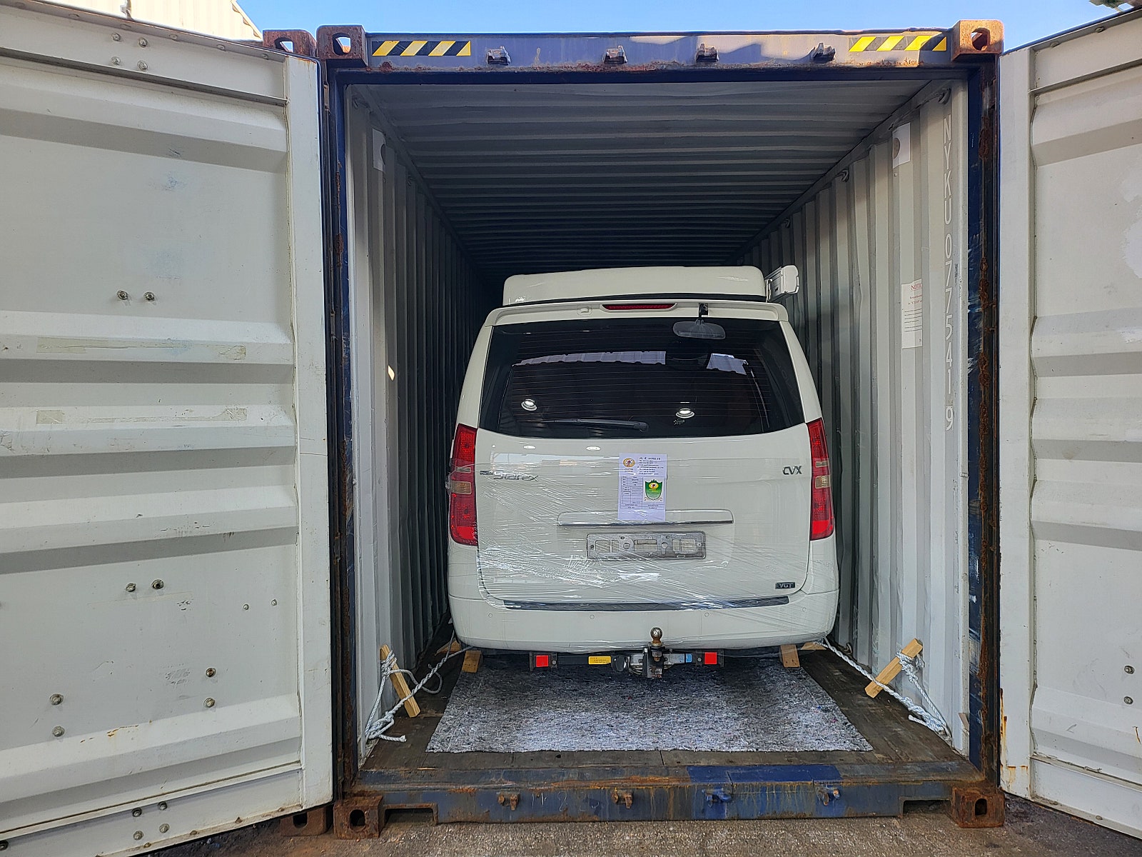 مؤخرة سيارة داخل حاوية وحبال تثبيت على الجانبين