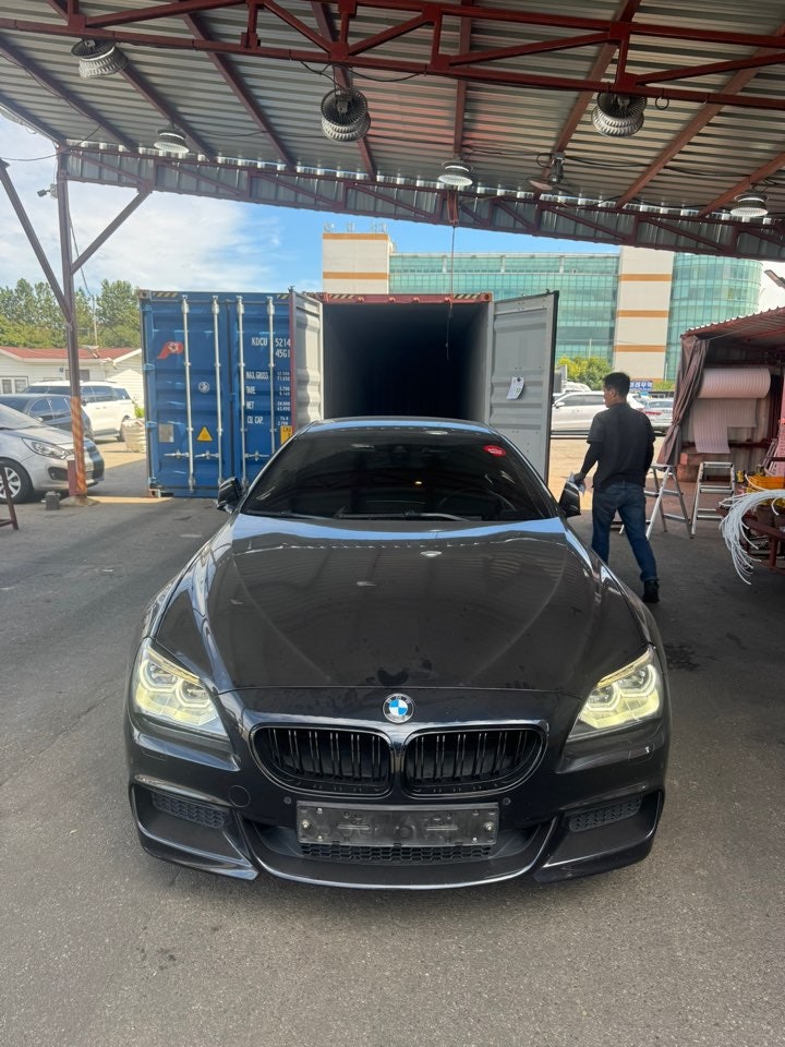 Frente de un BMW oscuro bajo el techo de la zona de carga.