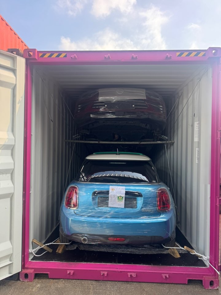مؤخرة هاتشباك زرقاء مغلفة تحت سيارة SUV حمراء داكنة مع حبال تثبيت.