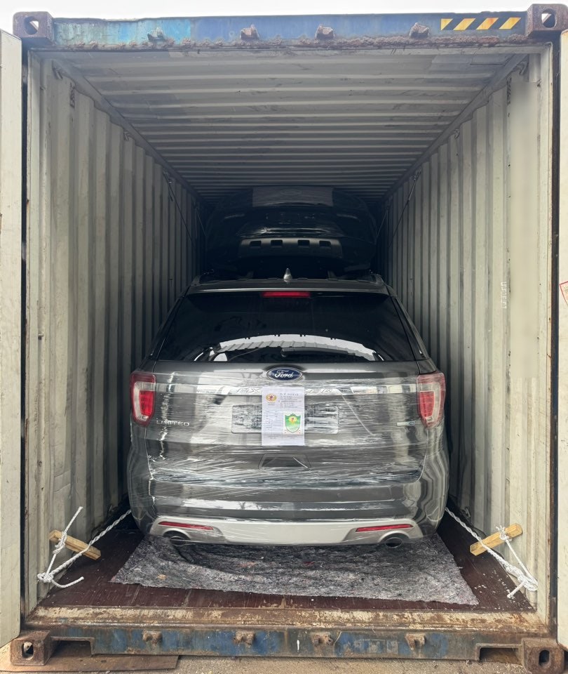 SUV на разной высоте внутри контейнера, канаты и деревянные детали вдоль пола.