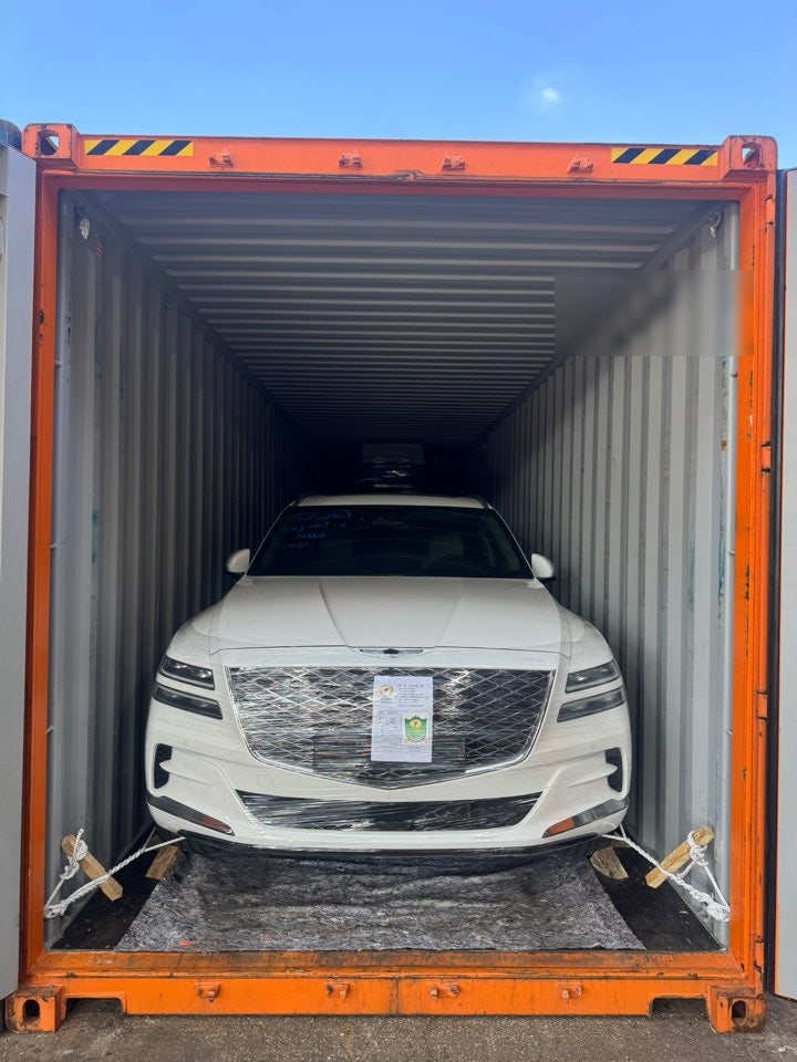 سيارة SUV بيضاء عند مدخل حاوية مفتوحة مع تغليف أمامي وحبال