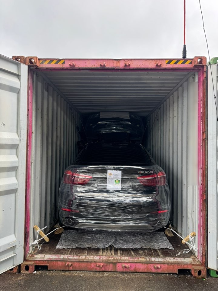 شارة X6 على مؤخرة SUV ملفوفة بغشاء واقٍ ومثبتة داخل حاوية.