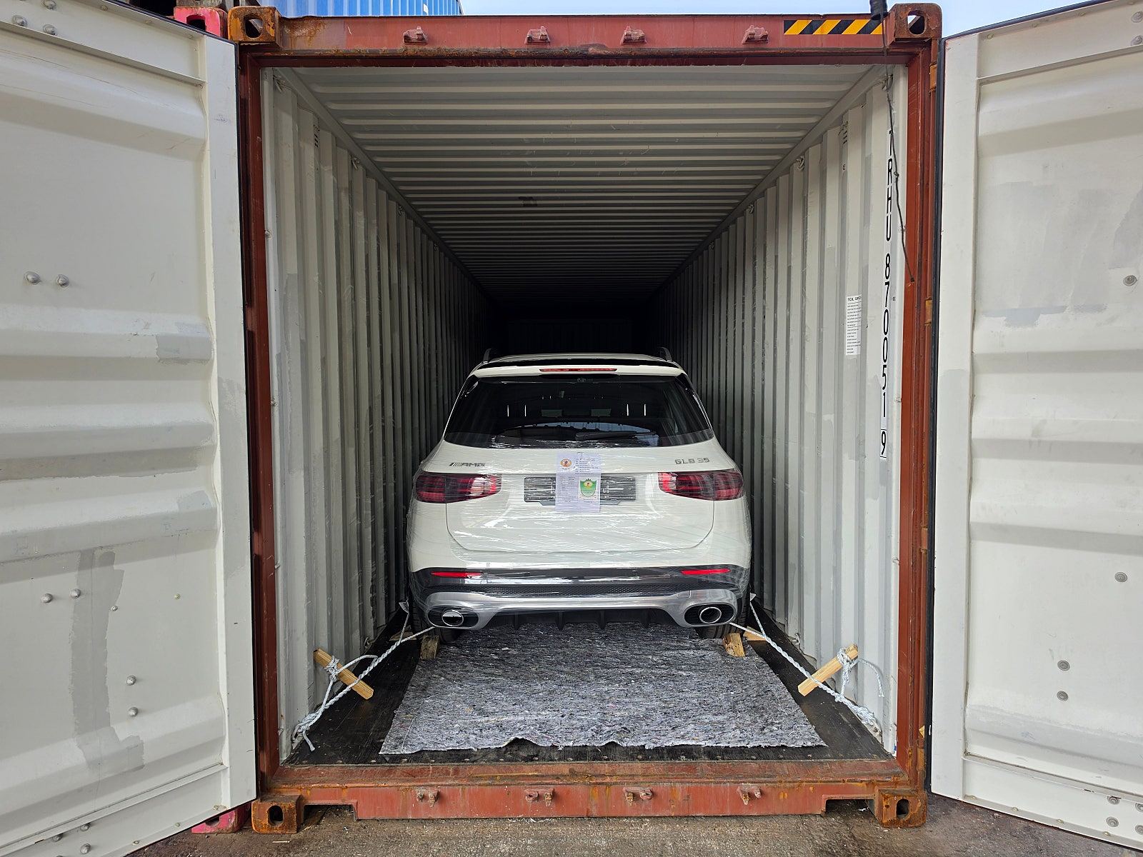 سيارة SUV، اللون: أبيض، المؤخرة مثبتة داخل حاوية.