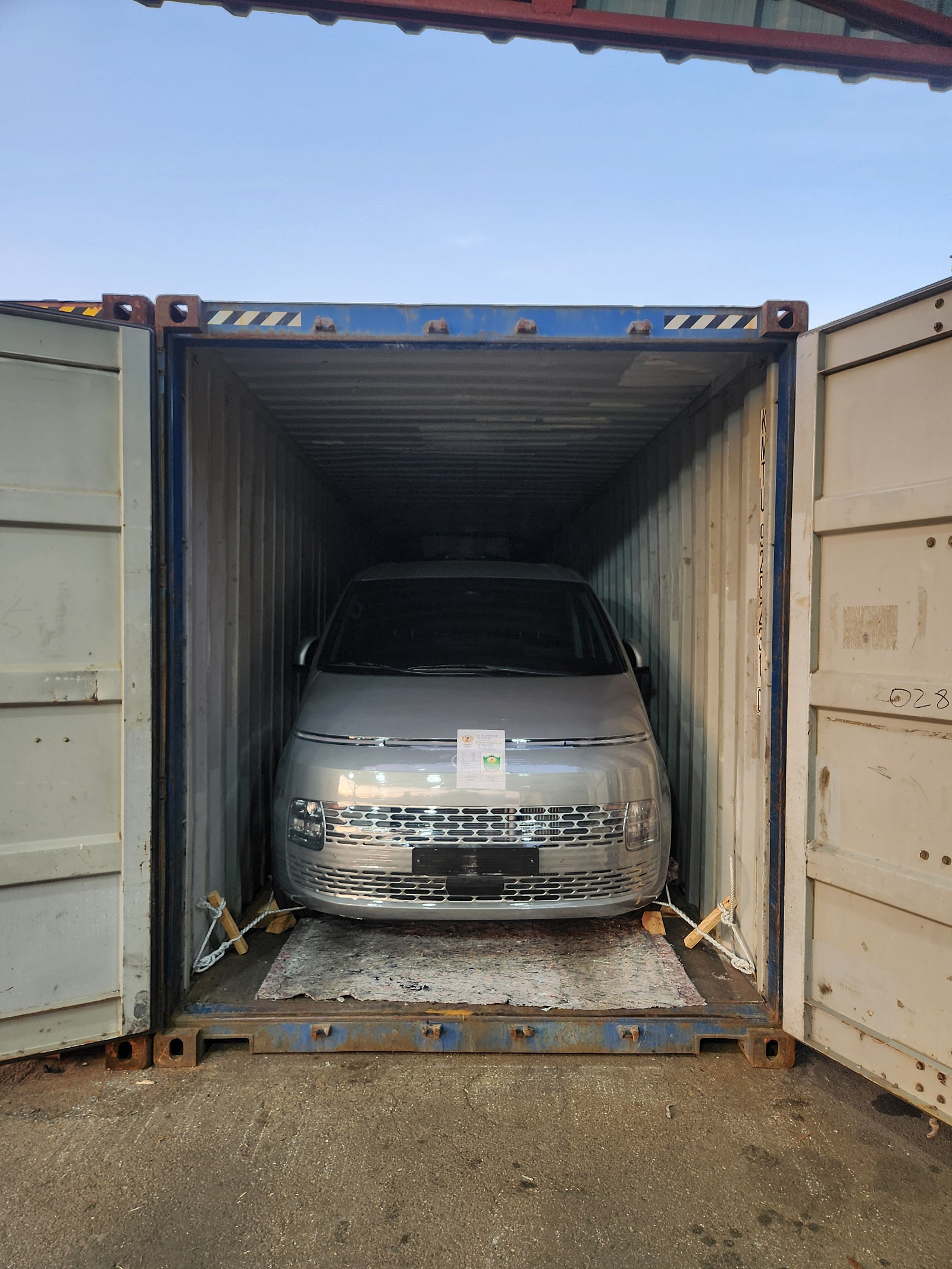 مقدمة سيارة داخل حاوية وحبال تثبيت على الجانبين