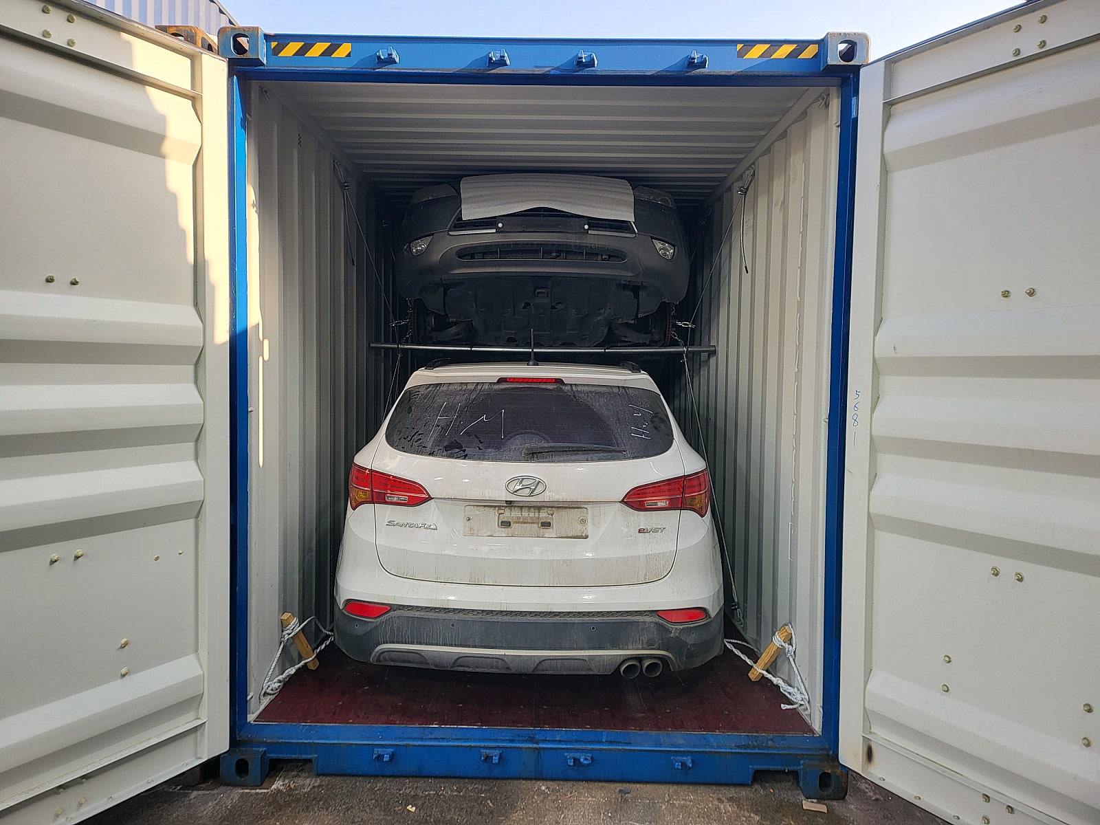 سيارة SUV، اللون: أبيض، المؤخرة مثبتة داخل حاوية.