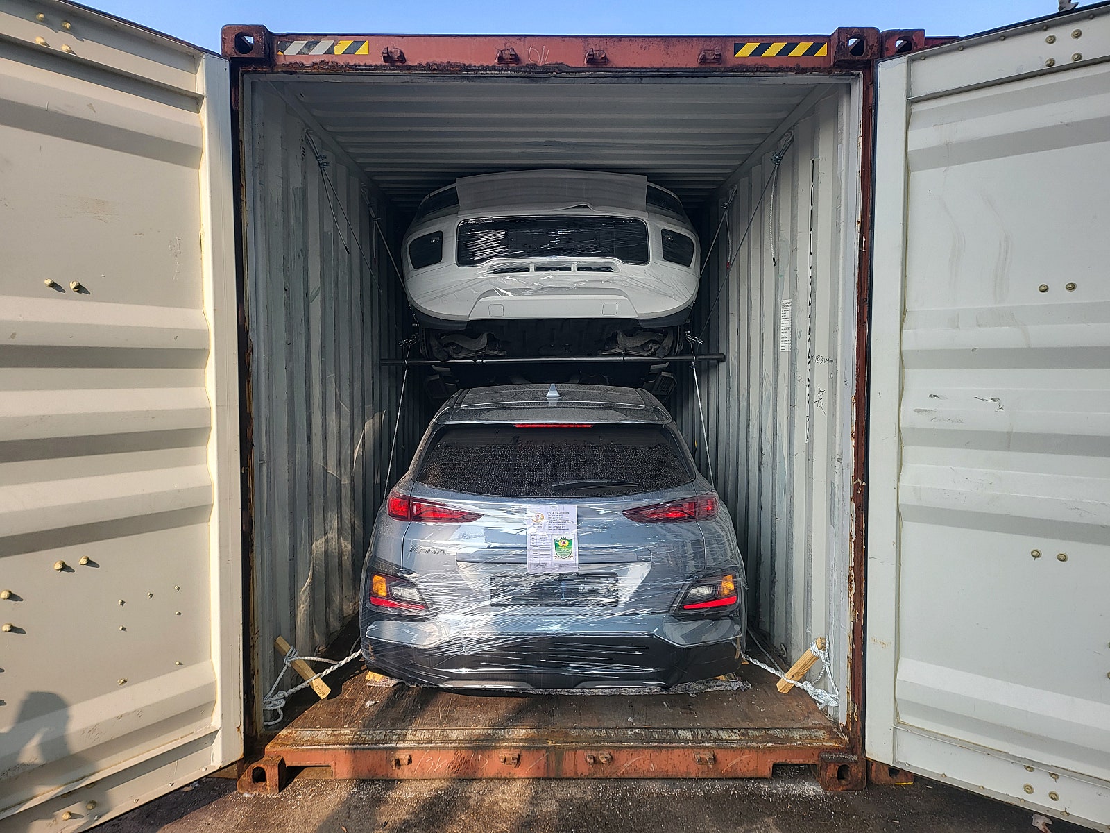 سيارة SUV، اللون: أزرق، المؤخرة مثبتة داخل حاوية.