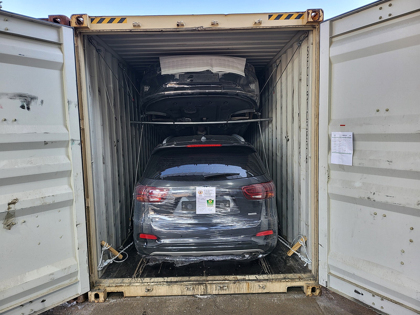سيارة SUV، اللون: أزرق، المؤخرة مثبتة داخل حاوية.