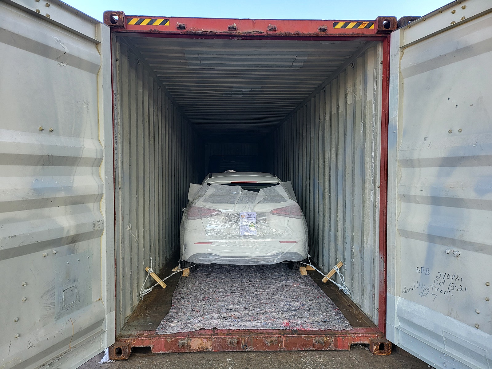 مؤخرة سيارة داخل حاوية وحبال تثبيت على الجانبين