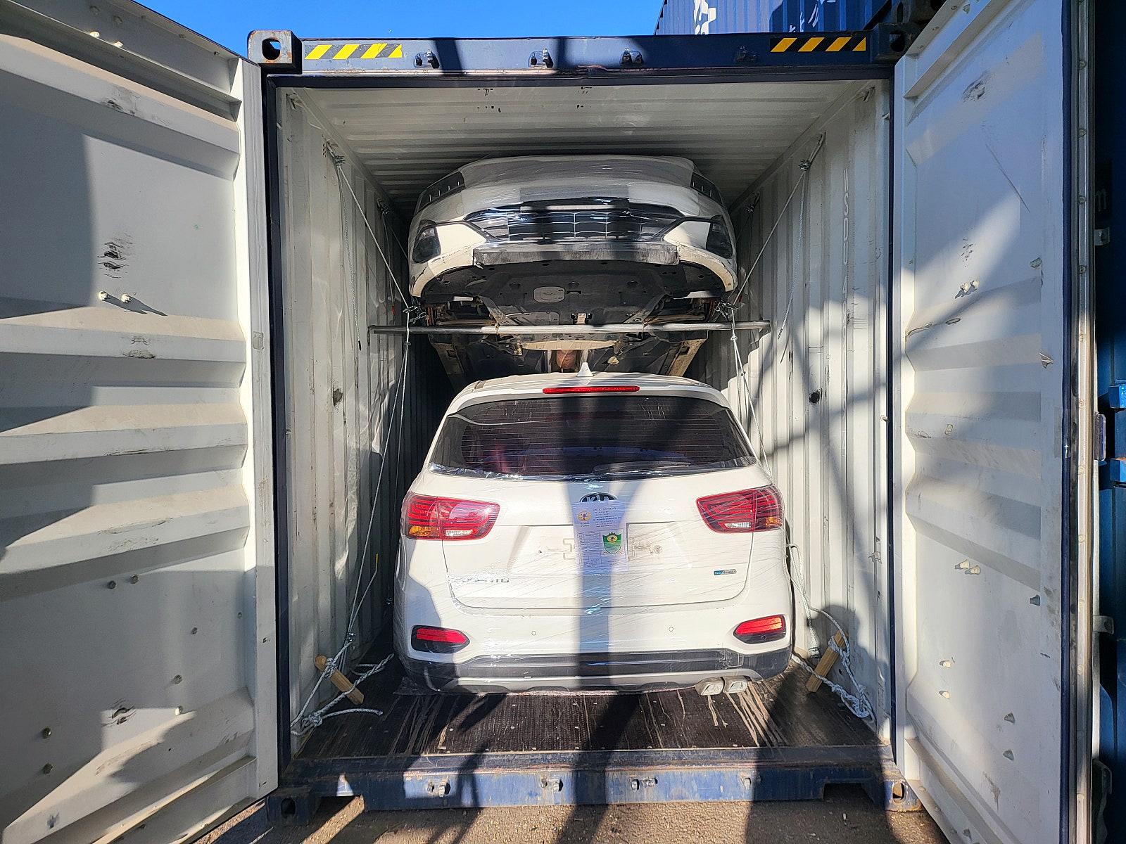 سيارة SUV، اللون: أبيض، المؤخرة مثبتة داخل حاوية.